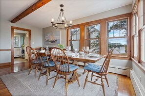 A dining area with a wooden table set for four, surrounded by wooden chairs with blue cushions.