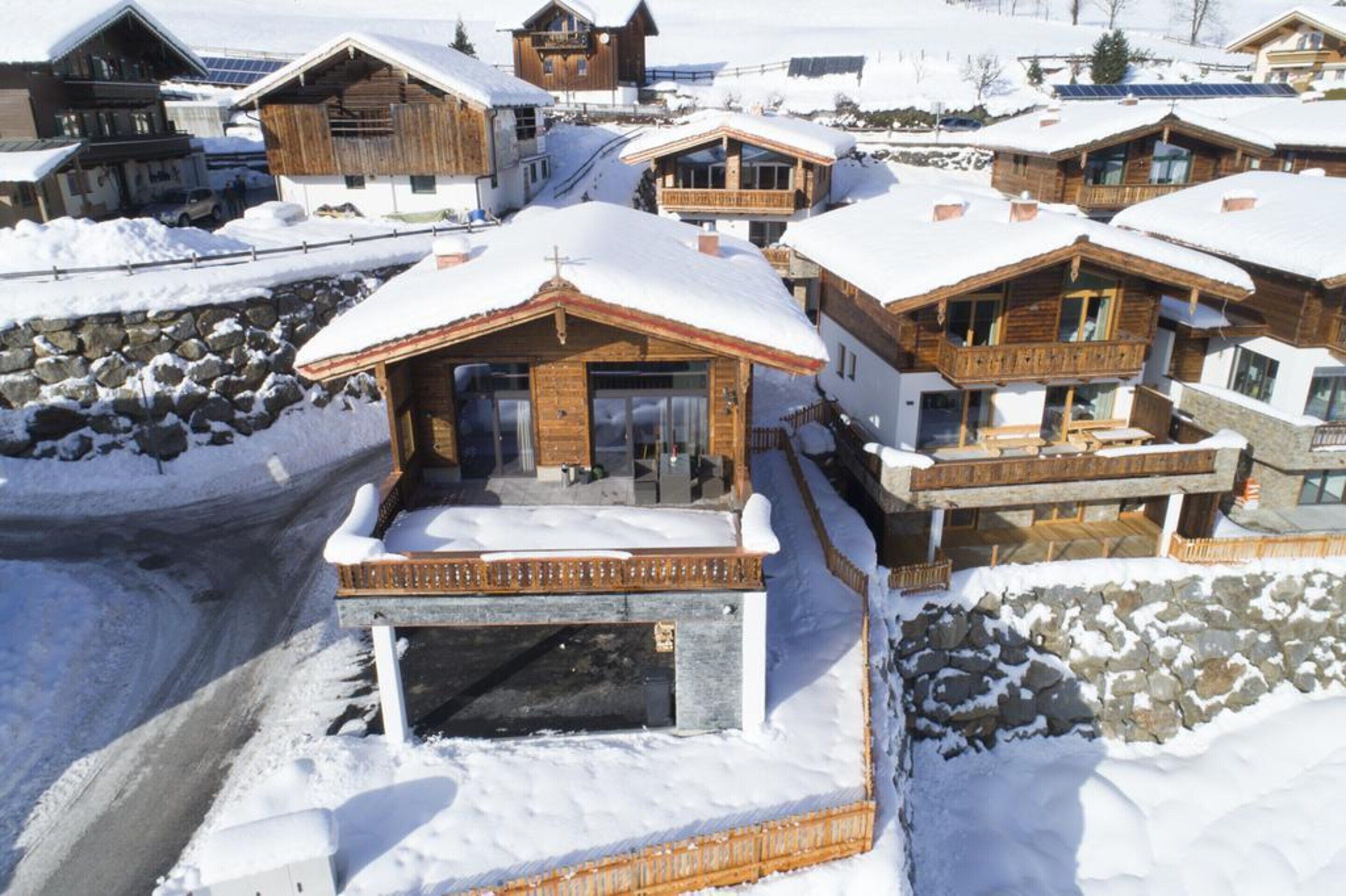 A snow-covered mountain lodge with wooden architecture, a stone entrance, and a balcony.