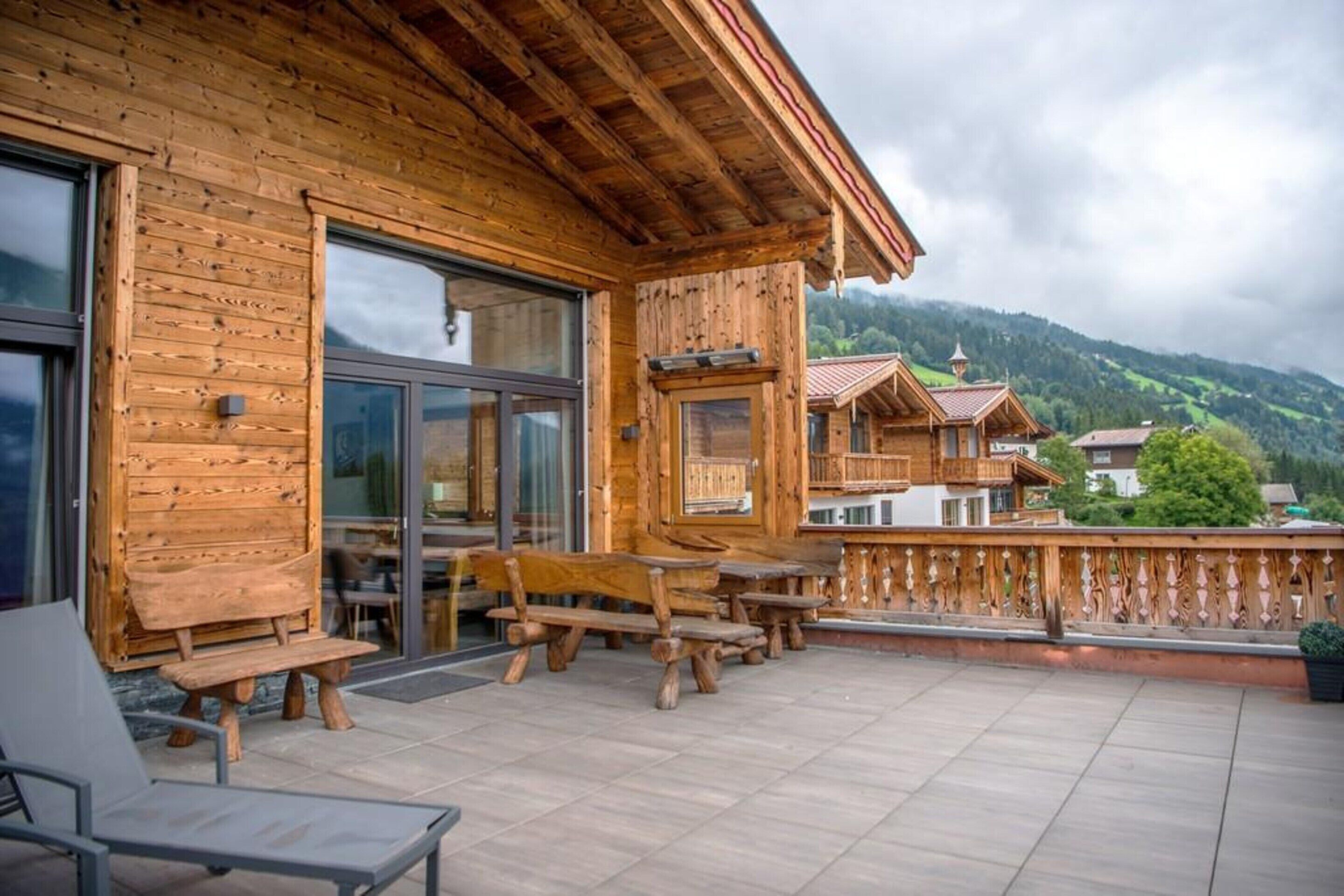 Una baita in legno con un balcone, posti a sedere all'aperto e vista sulle montagne.