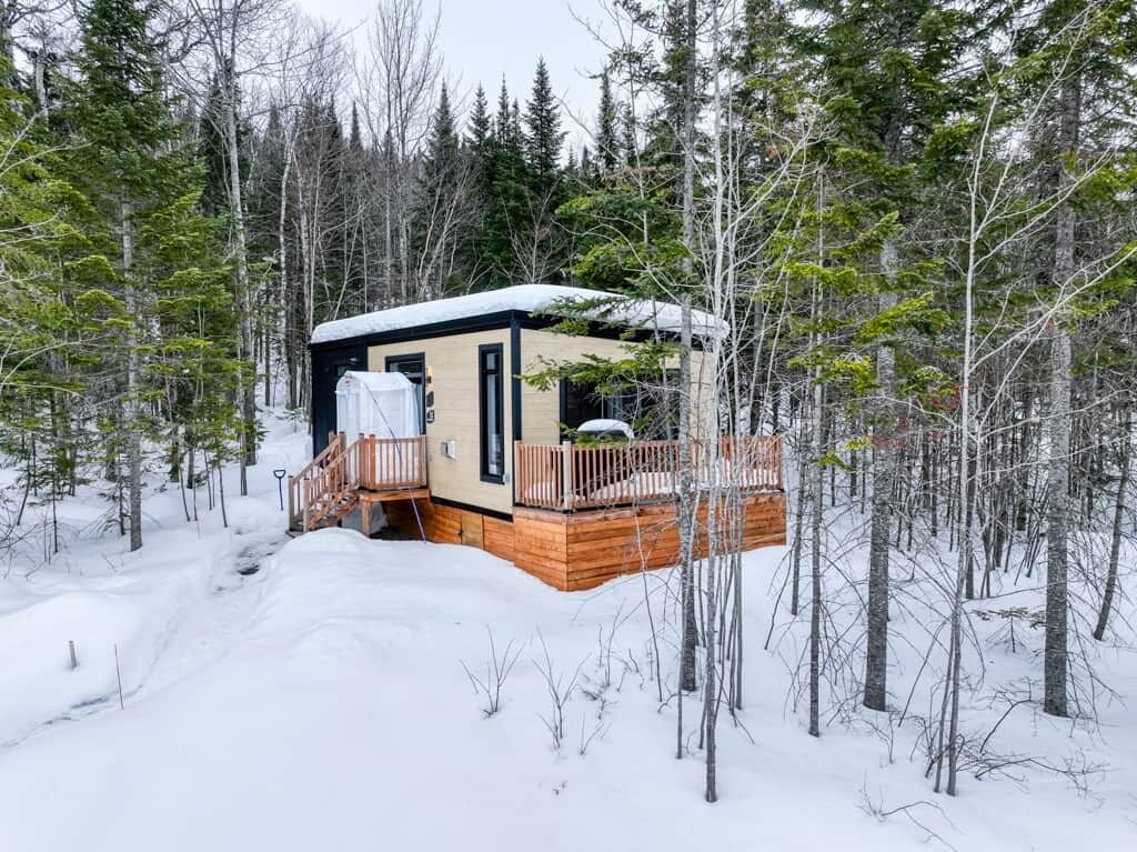 Una baita con veranda in legno, zona esterna coperta e paesaggio innevato.