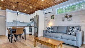 A modern kitchen with white cabinets, a stainless steel refrigerator, and a dining area with a table and chairs. - Hôtel à la maison - Le Cocon, ski et golf (Adstock)