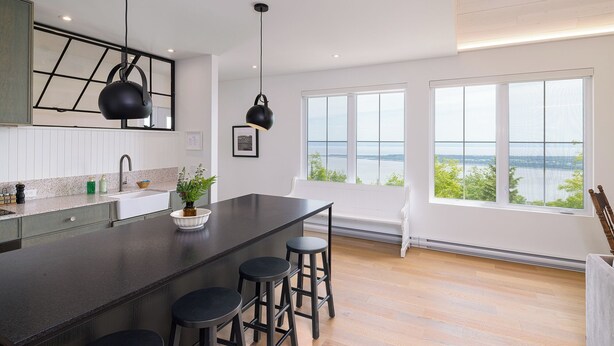 Una cocina moderna con una isla grande, taburetes de bar y vista al agua.