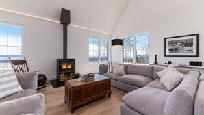 Una sala de estar moderna con chimenea, ventanas amplias y un rincón de descanso acogedor.