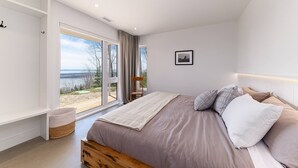 Un dormitorio con una cama grande, vistas al exterior y una ventana con cortinas.