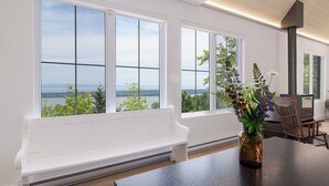 Un interior moderno con ventanas amplias que ofrecen vistas a un cuerpo de agua y vegetación.