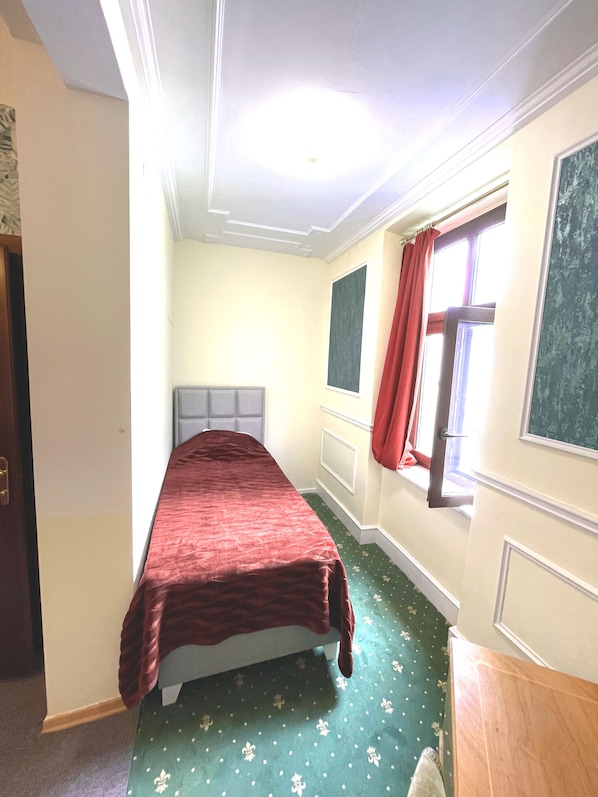 A room with a bed, a window with red curtains, and a green patterned carpet. - Hotel Viki (Vienna)