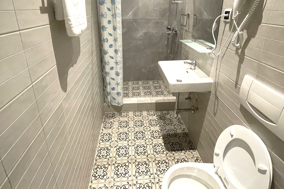 A bathroom with a shower, toilet, and sink.