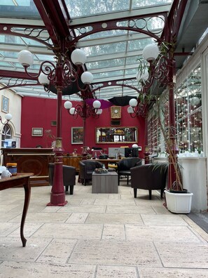 A conservatory with a red interior, featuring a wooden desk, two black sofas, and a coffee table. - Hotel Viki (Vienna)