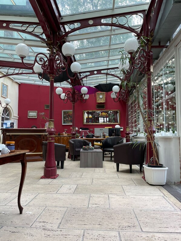 A conservatory with a red interior, featuring a wooden desk, two black sofas, and a coffee table. - Hotel Viki (Vienna)