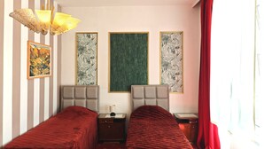 Una habitación de hotel con dos camas, una araña y tres cuadros enmarcados en la pared.