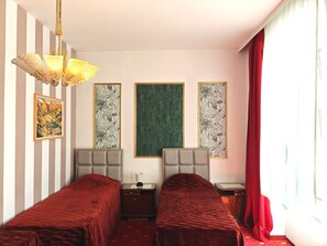 A hotel room with two beds, a chandelier, and three framed artworks on the wall. - Hotel Viki (Vienna)