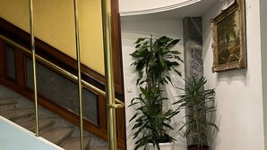A lobby with a marble floor, a staircase with golden railings, and potted plants. - Hotel Viki (Vienna)