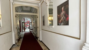 A hallway with a red carpet, white walls, and a large mirror. - Hotel Viki (Vienna)