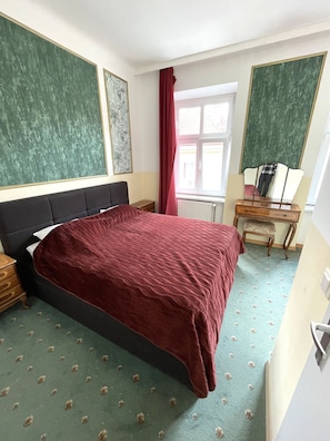 A bedroom with a large bed, a wooden nightstand, a dresser, and a window with curtains. - Hotel Viki (Vienna)