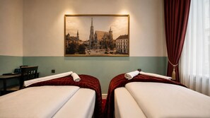 Une chambre d’hôtel avec deux lits, un bureau et un grand tableau encadré représentant une cathédrale, accroché au mur.
