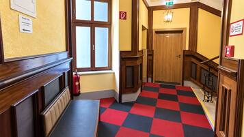 Ein Hotelgang mit Schachbrettboden, einer Bank und einem Feuerlöscher.