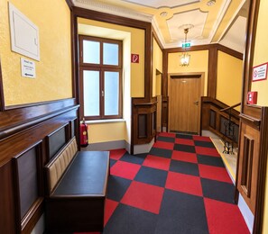 A hotel hallway with a checkered floor, a bench, and a fire extinguisher. - Hotel Viki (Vienna)