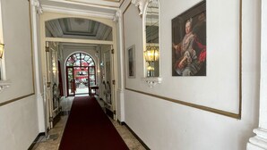 Un pasillo con alfombra roja, paredes blancas y un espejo grande.