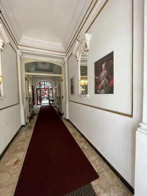 A hallway with a red carpet, white walls, and a large mirror. - Hotel Viki (Vienna)