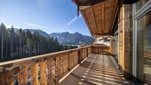 Ein Holzbalkon mit Blick auf einen Wald und Berge.