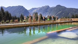 Eine Gruppe von Menschen steht an einem Pool vor einer Berglandschaft.