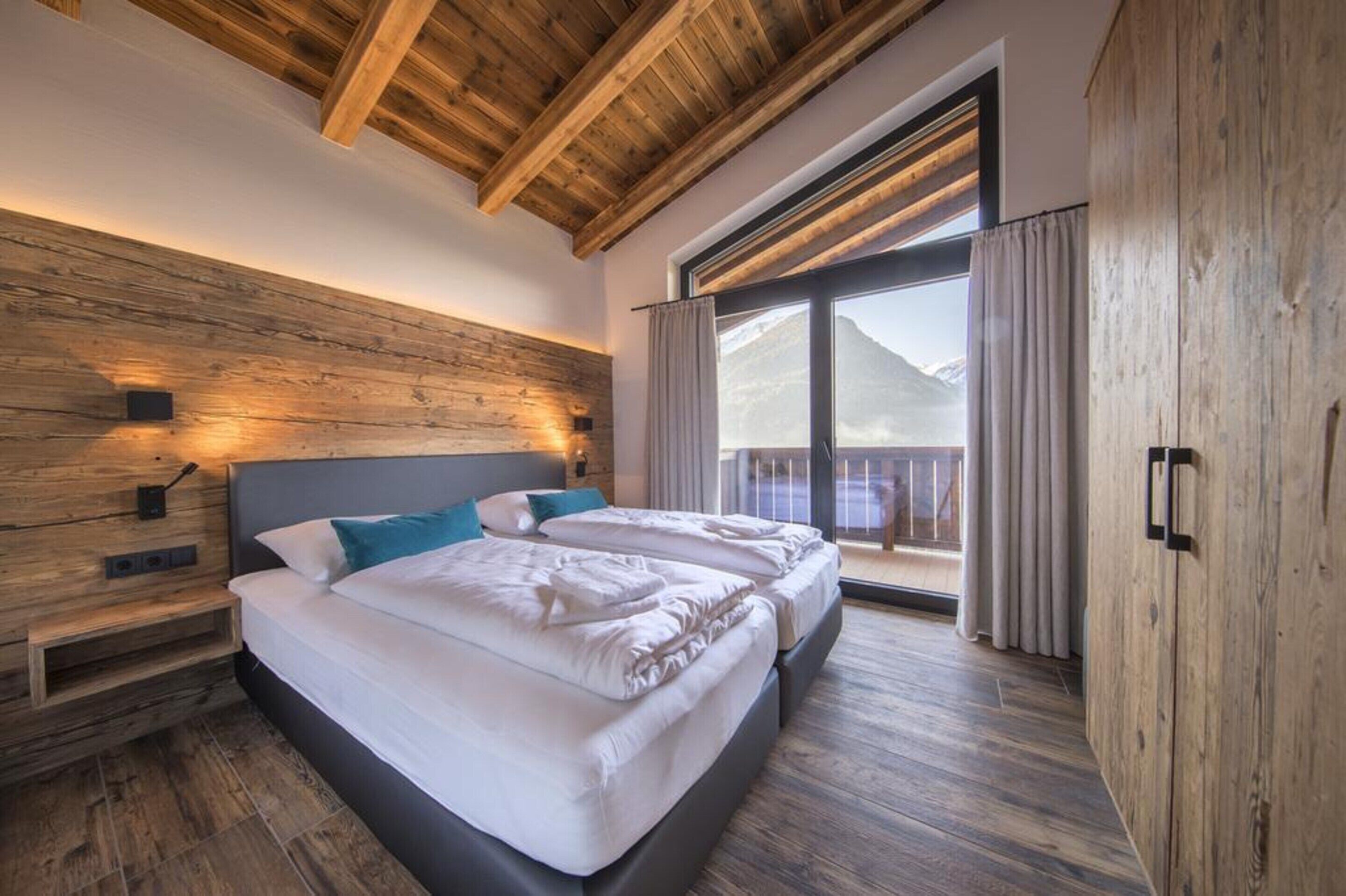 A modern bedroom with a wooden ceiling, a large window with curtains, and a balcony.