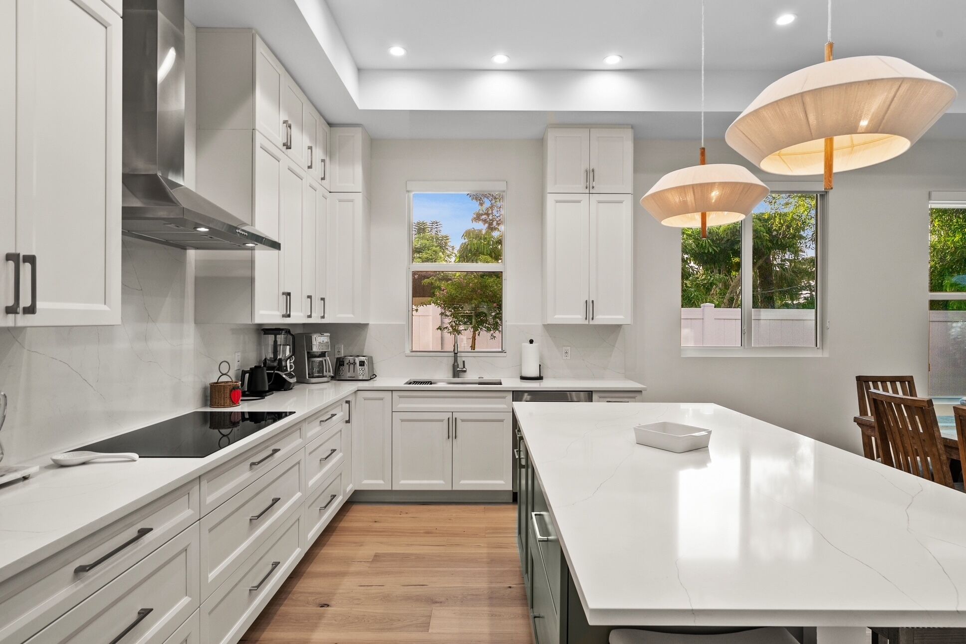 A modern kitchen with white cabinets, a large island, and pendant lighting.