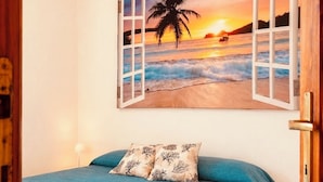 A bedroom with a bed, a pillow, and a wall art depicting a beach scene. - Costa Rei - House 500 meters from the sea, climate, sea view terrace and garden  (Costa Rei)