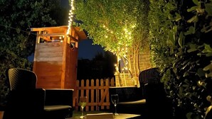 An outdoor seating area with a wooden pergola, string lights, and a white picket fence. - Costa Rei - House 500 meters from the sea, climate, sea view terrace and garden  (Costa Rei)