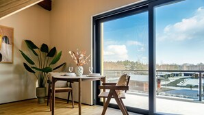 Een moderne eetruimte met een houten tafel, stoelen en een groot raam met uitzicht op een besneeerd landschap.