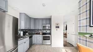 A modern kitchen with grey cabinets, stainless steel appliances, and a tiled backsplash. - Escape to the Poconos | Hot Tub, Sauna, Mini-Golf (East Stroudsburg)