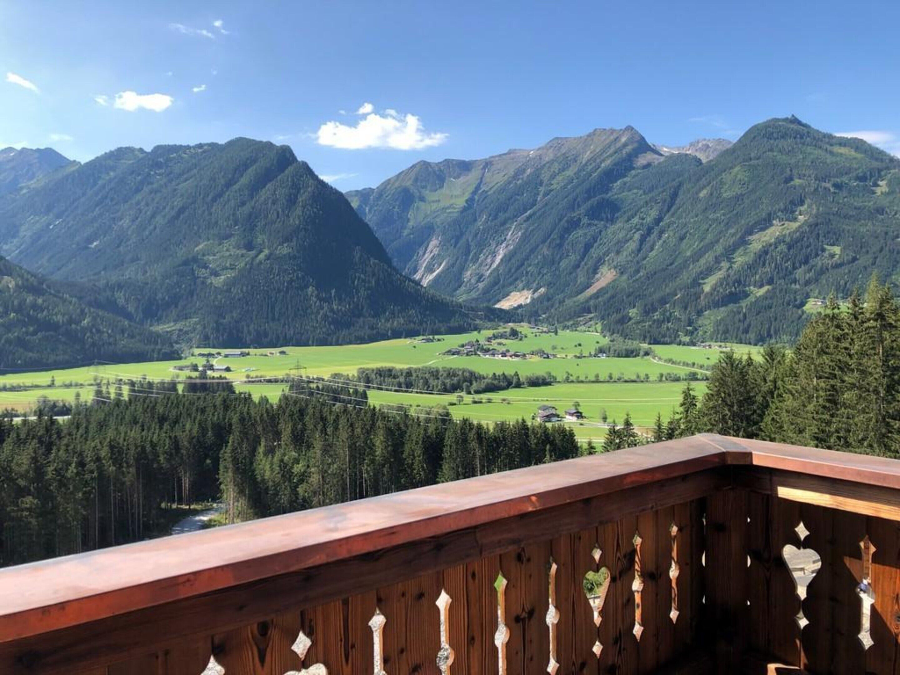 Ein hölzerner Balkon mit Blick auf eine Berglandschaft und ein Tal.