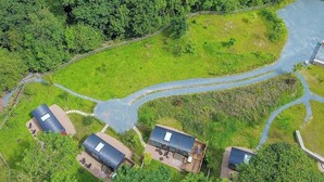 An aerial view of a property with three buildings, a winding road, and a river. - The Holt, a Stunning Cumbrian Shepherd’s Hut (Carnforth)
