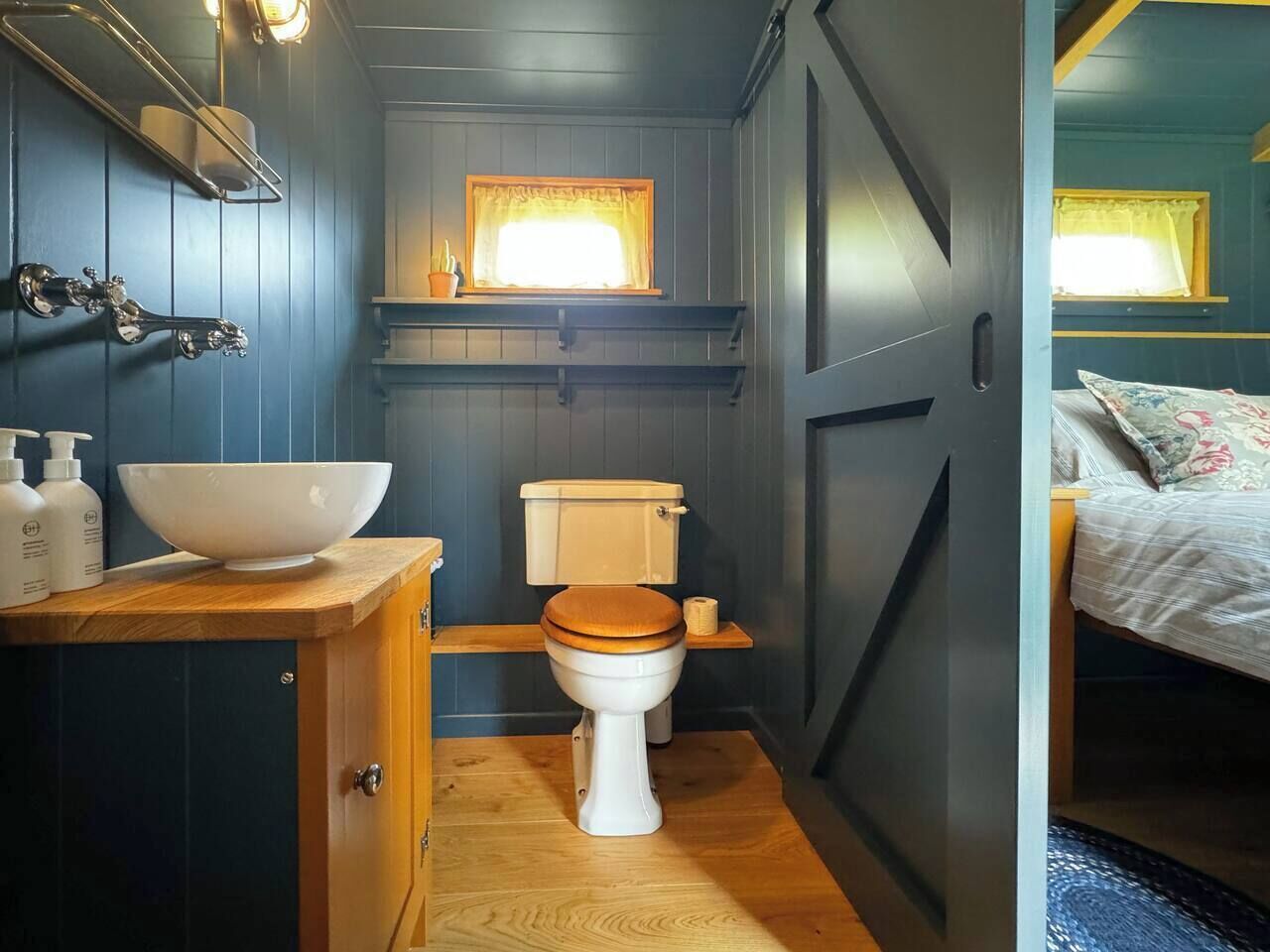 A compact bathroom with a white toilet, wooden vanity, and a large basin.