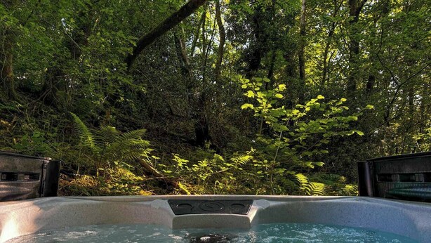 A hot tub surrounded by lush greenery. - The Sett, a Stunning Shepherd’s Hut & Hot Tub (Carnforth)