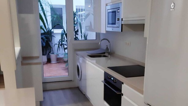 A compact kitchen with a washing machine, a microwave, and a refrigerator.