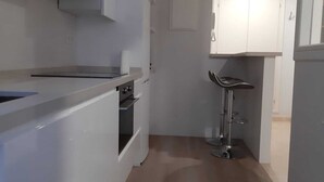 A modern kitchen with white cabinetry, a built-in microwave, and a stainless steel sink.