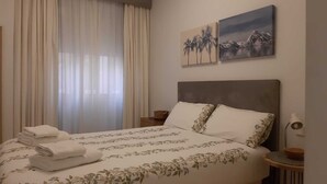 A hotel room with a bed, a nightstand, a lamp, and two paintings on the wall.