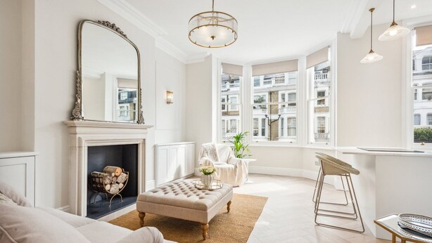 Ein modernes Wohnzimmer mit Kamin, einem großen Spiegel und Blick auf die Stadt durch bodentiefe Fenster.
