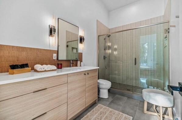A modern bathroom with a wooden vanity, a glass shower enclosure, and a white toilet.