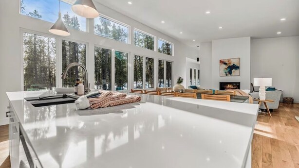 Una cocina espaciosa con una isla grande, una zona de comedor con sillas de madera y una chimenea.