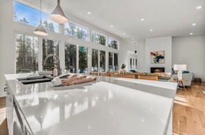 A spacious kitchen with a large island, a dining area with wooden chairs, and a fireplace.