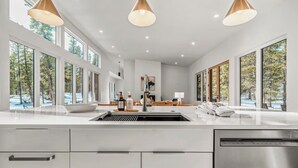 Una cocina moderna con ventanas amplias, una isla central e iluminación colgante.