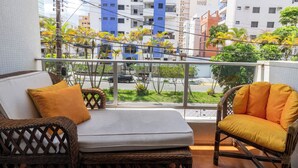 A balcony with wicker furniture and a view of a cityscape. - Condomínio Praia de Taormina (Guaruja)