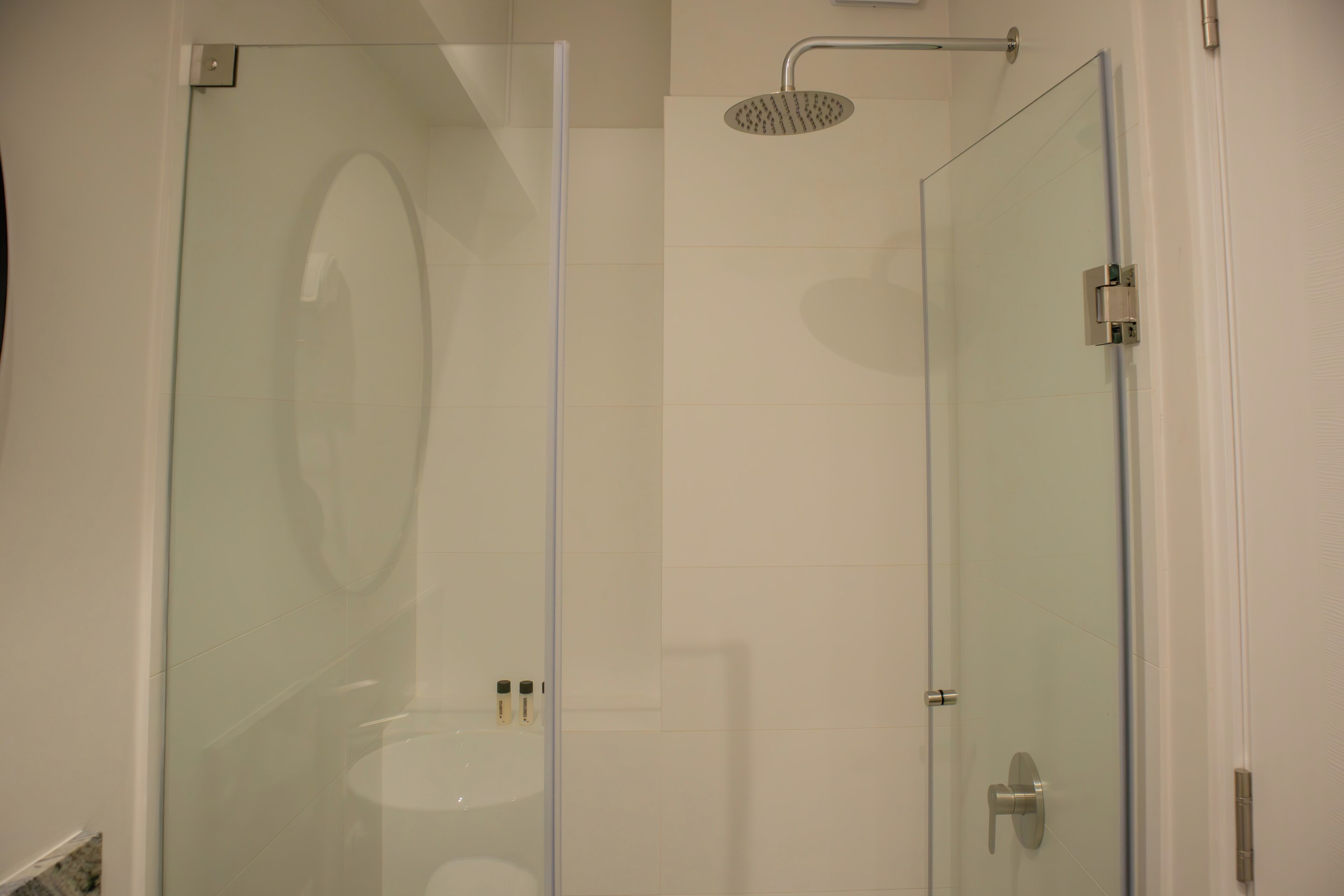 A glass-enclosed shower with a handheld showerhead and a glass door.