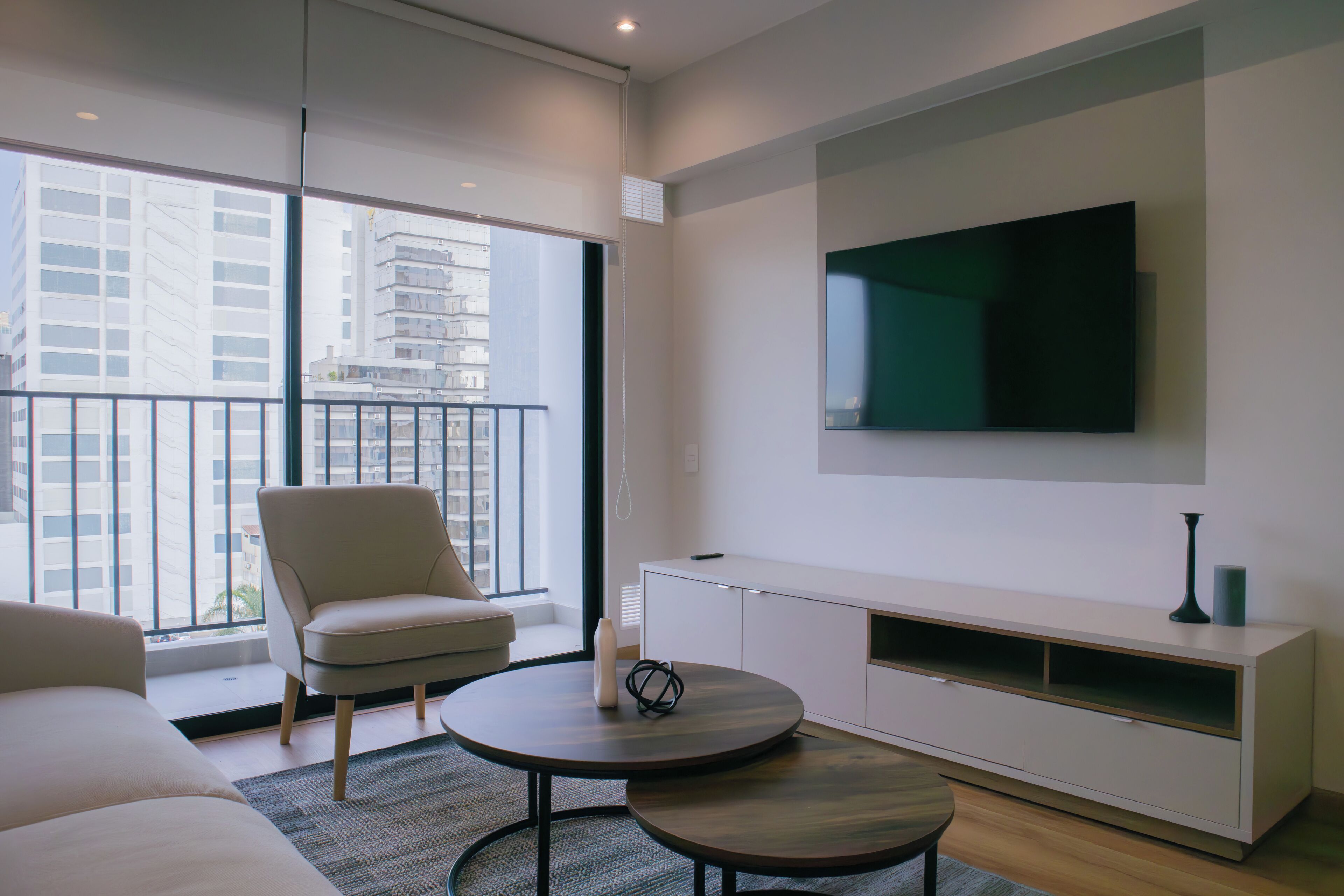 A modern living room with a large TV, a sofa, a chair, and a coffee table.