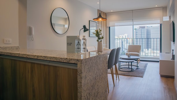 Une cuisine moderne avec un plan de travail en granit, un miroir rond et une suspension lumineuse.