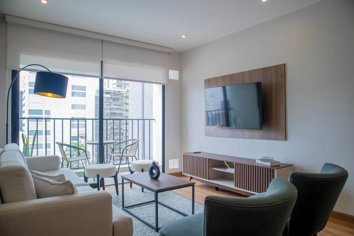 A modern living room with a sofa, chairs, a coffee table, and a TV mounted on the wall.