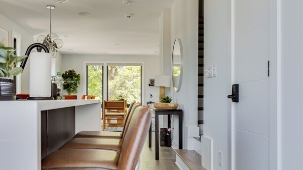 Una cocina moderna con una isla central, asientos tipo banco de madera y vistas al exterior.