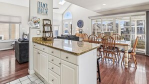 Una cocina amplia con una isla grande, armarios blancos y un comedor con sillas de madera.